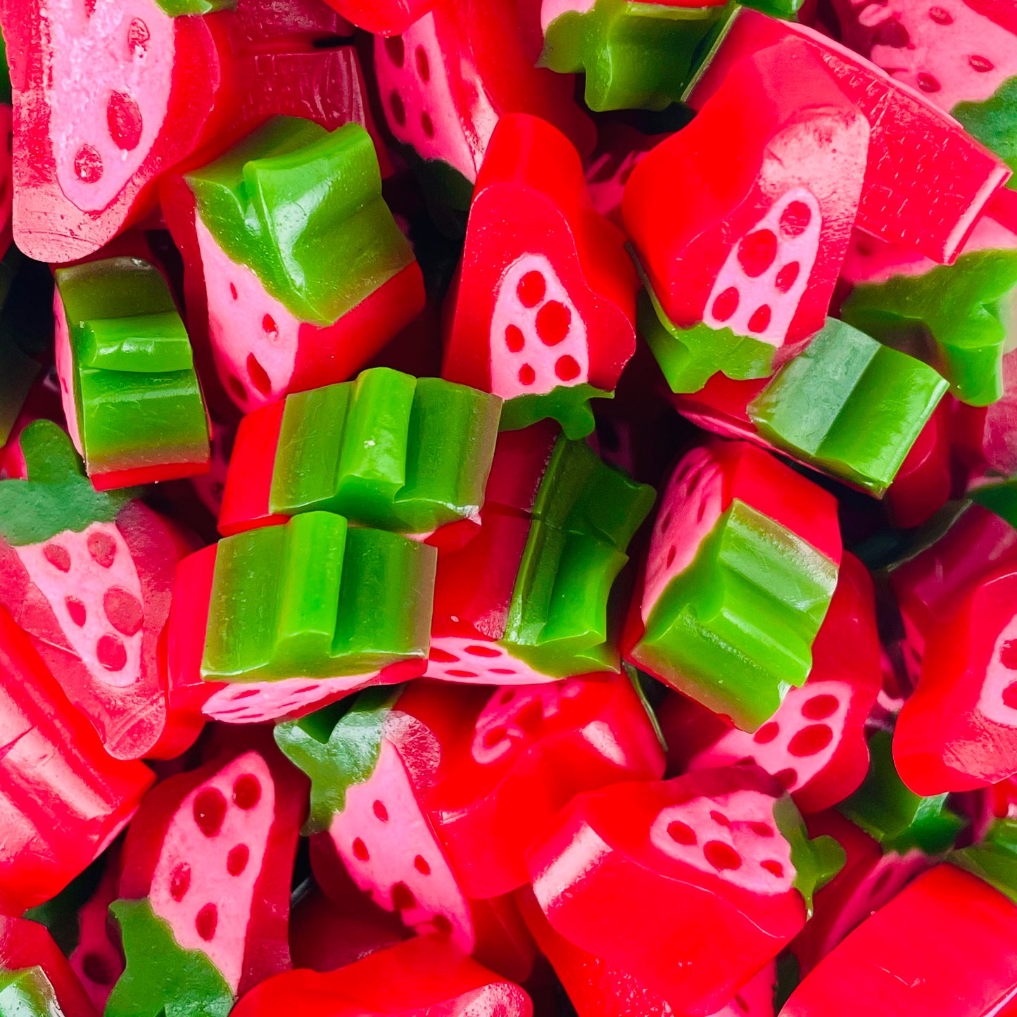 Red and green strawberry shaped and flavoured sweets with liquorice dots in the middle 