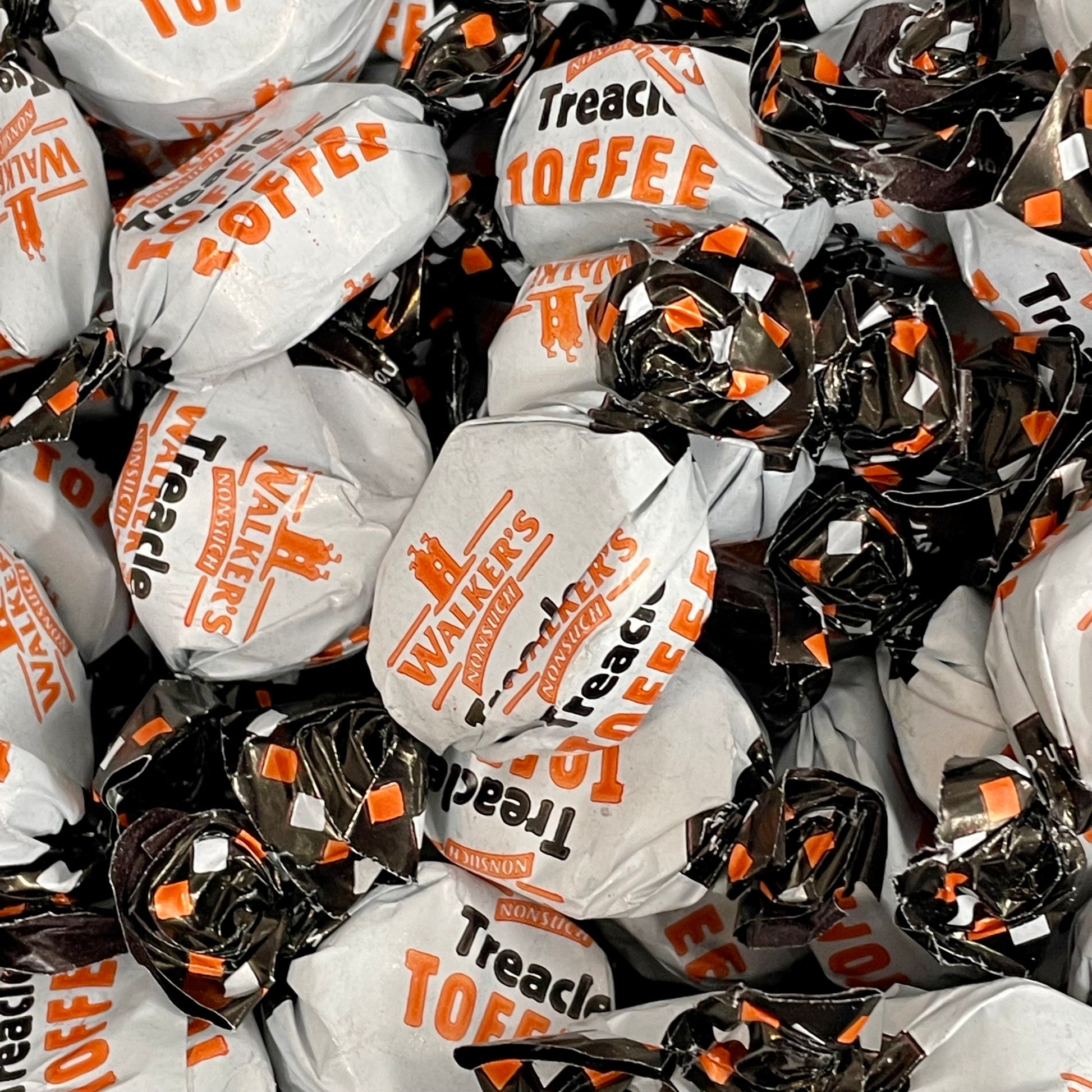 Pile of Walker's Treacle Toffee individually wrapped in a orange, black and white wrapper 